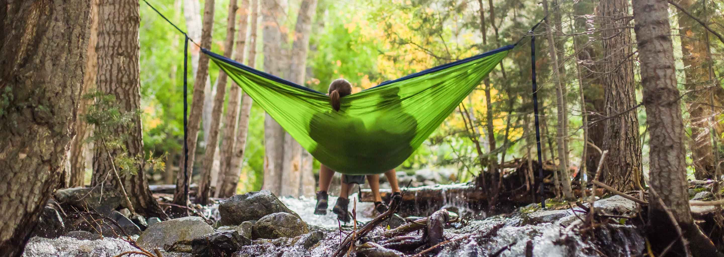 Campers lounge in a hammock above a stream