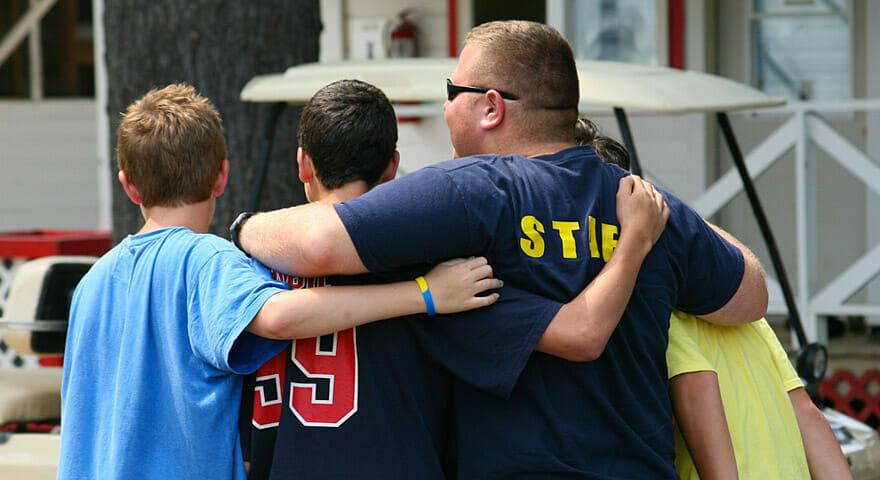 group of boys hugging their camp counselor